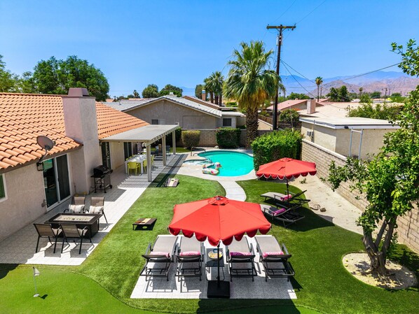 A backyard with a swimming pool, outdoor seating, and a patio area.