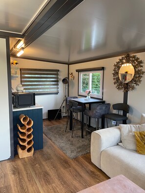 A compact living space with a kitchenette, a dining area with a table and chairs, a sofa, and a decorative mirror. - Birch Tree Lodge, Sleeps 4, Set in 3 Acres (Otley)