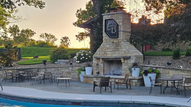 A poolside area with a stone fireplace, outdoor seating, and a view of the surrounding landscape. - King Cabin Room Lark Spur (Maple Hill)