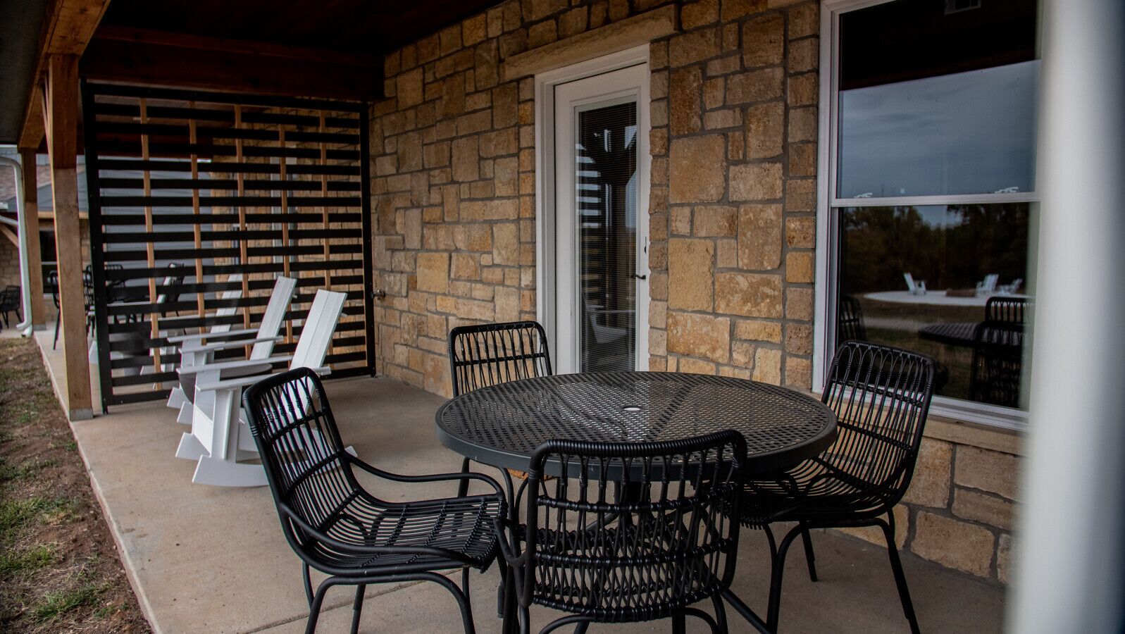 A patio with a round table and four chairs, a wooden fence, and a stone wall.