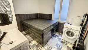 A compact laundry room with a washing machine, a drying machine, and a window providing natural light.