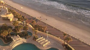 A resort with a swimming pool, beach access, and palm trees.