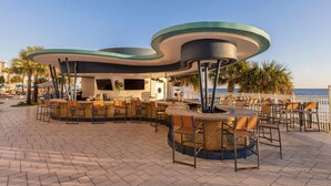 An outdoor bar area with seating and a view of the sea.