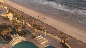 Un resort con piscina, acceso a la playa y palmeras.