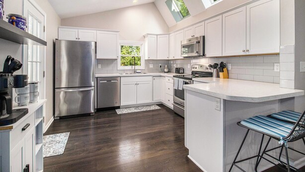 A modern kitchen with white cabinets, stainless steel appliances, and a central island with bar stools. - Charming 3-bedroom house close to Promedica and UToledo (Toledo)