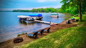 A lakeside dock with boats, a covered area, and outdoor seating.