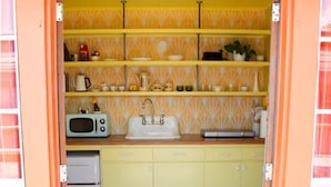 Een kleine keuken met gele en witte betegeling, een wit spoelbak en een kleine, witte koelkast.