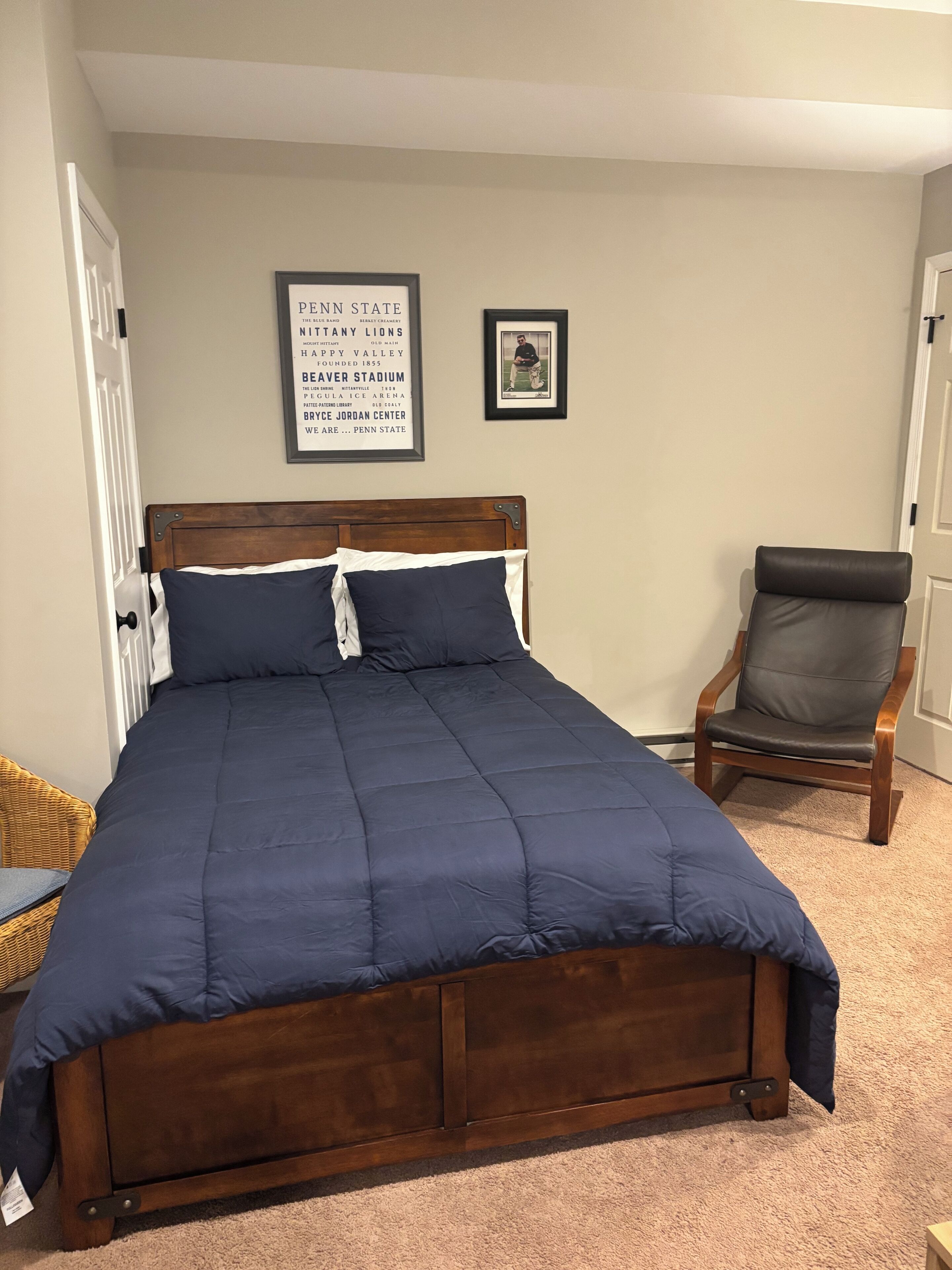 A bedroom with a wooden bed, a chair, and a framed sign on the wall.