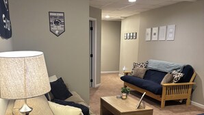 Una sala de estar con un sofá beige, un sofá azul oscuro, una mesa de centro de madera y una lámpara.