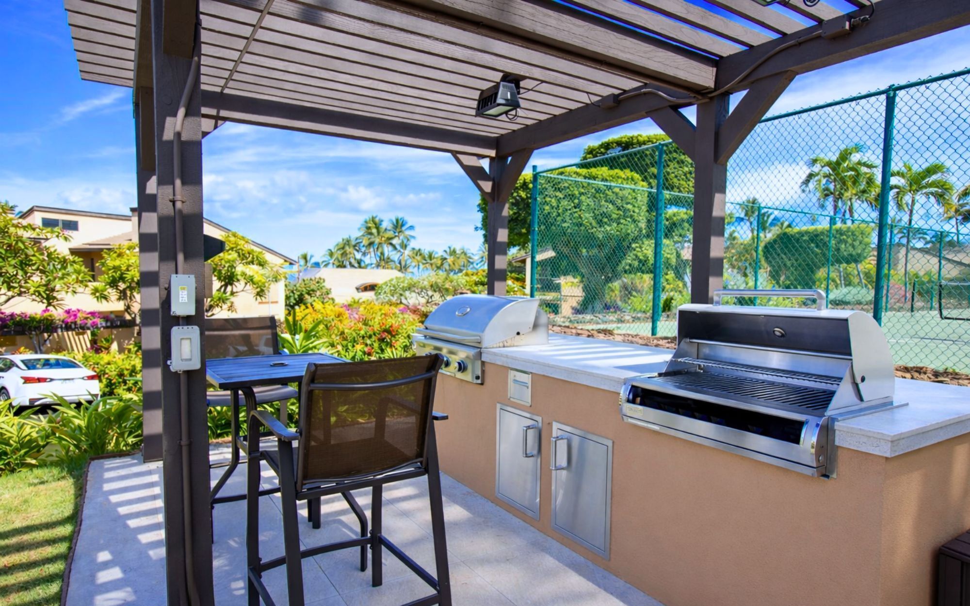 An outdoor patio with a grill, seating, and a view of a residential area.