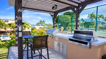 An outdoor patio with a grill, seating, and a view of a residential area.