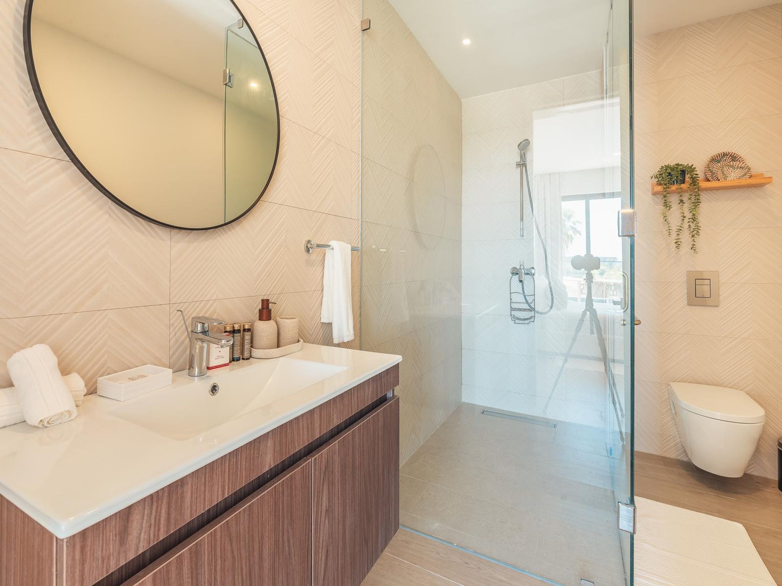 Ein modernes Badezimmer mit einer gläsernen Dusche, einem großen Spiegel und einem Holzlagerfläschchen.