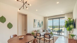 Ein modernes Wohnzimmer mit Essbereich, großen Fenstern und Blick ins Freie.