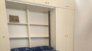 Une chambre à coucher avec un lit, une armoire et une étagère sur laquelle est posée une photo encadrée.