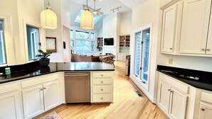 Un'ampia cucina con un'isola grande, mobili bianchi e un lucernario.