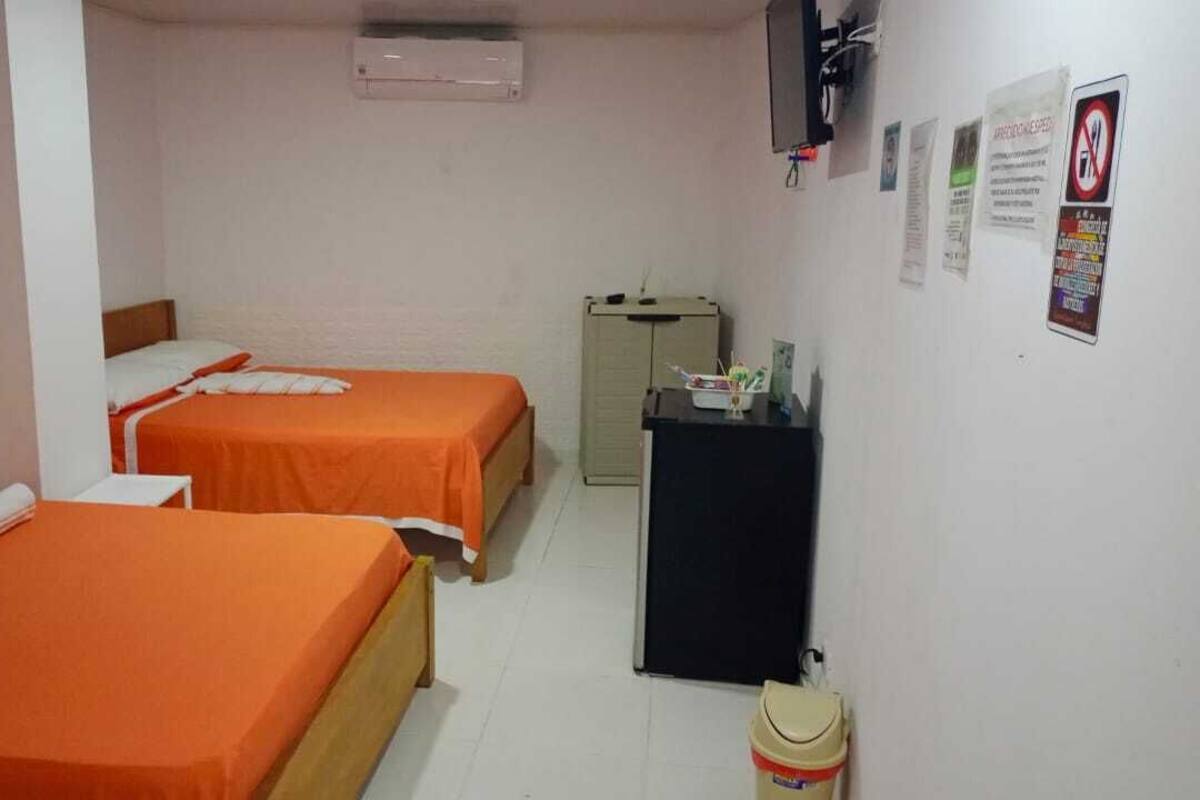 A hotel room with two beds, a small desk, and a cabinet.