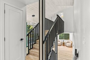 Un escalier moderne avec des rampes noires, un plancher en bois et une vue sur l’extérieur.