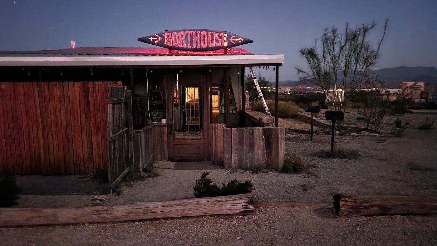 Un edificio rústico con un letrero de neón que dice “ROTHOUSE” y fachada de madera.
