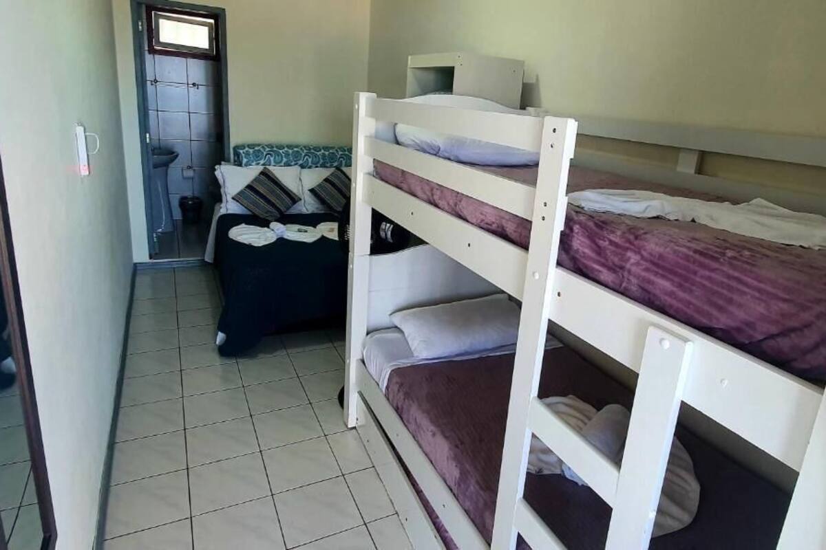 A dormitory room with bunk beds, a small desk, and a chair.