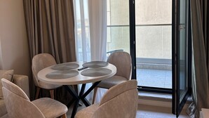 A modern living room with a round table, four chairs, a ceiling light fixture, and a sliding glass door leading to an outdoor area. - Modern Seaside Retreat · Stunning Sea View (Constanța)