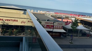 A view from a balcony overlooking a beachside area with outdoor seating and a Coca-Cola branded restaurant. - Modern Seaside Retreat · Stunning Sea View (Constanța)