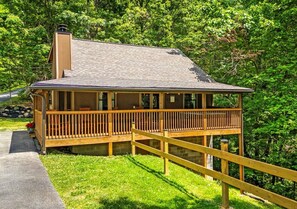 Eine zweistöckige Holzhütte mit Balkon, umgeben von üppigem Grün.