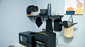 Eine Küche mit Mikrowelle, Toaster und einer Speisekammer mit Geschirr und Besteck.