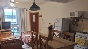 Eine kompakte Küche mit Esstisch, Stühlen, Kühlschrank, Mikrowelle und Herd.