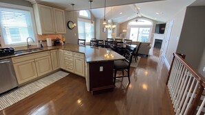 Una cocina amplia con una isla grande, piso de madera y un comedor con sillas y mesa.