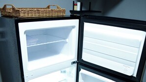 A black refrigerator with two door compartments, a basket on top, and a shelf above the door.