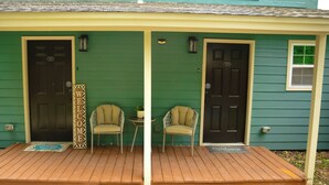 A porch with two doors, a welcome sign, two chairs, a small table, and a doormat.