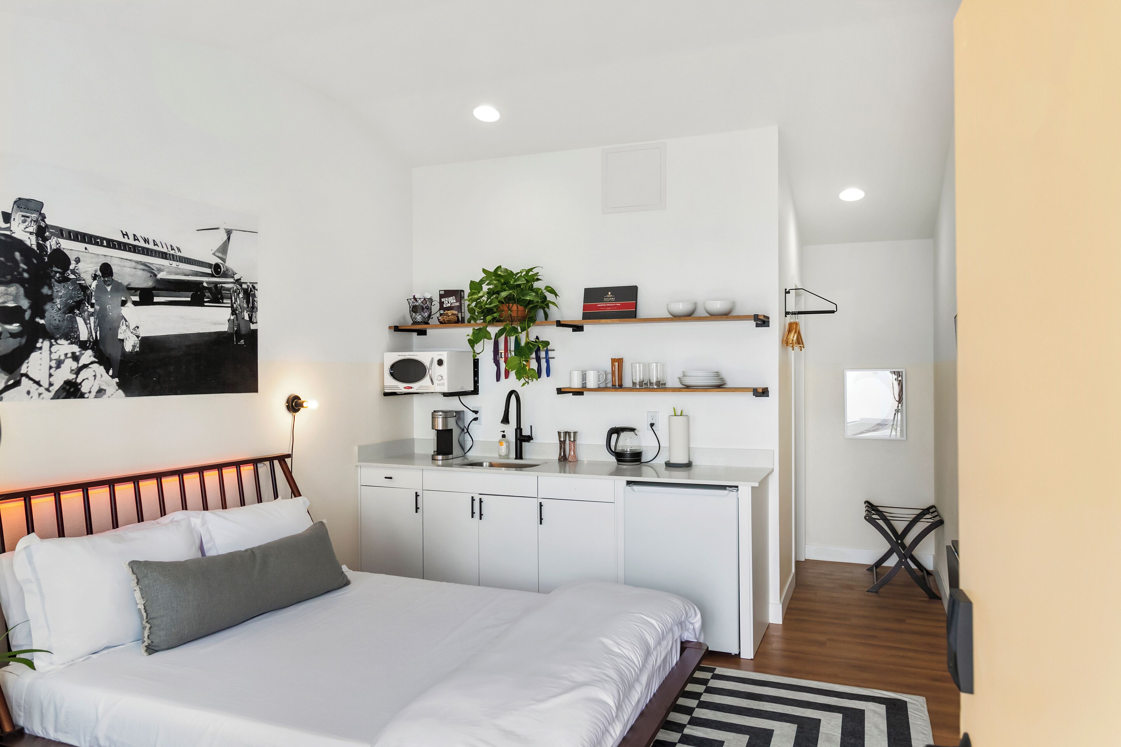 Una camera d'albergo moderna con letto, angolo cottura e bagno piccolo.