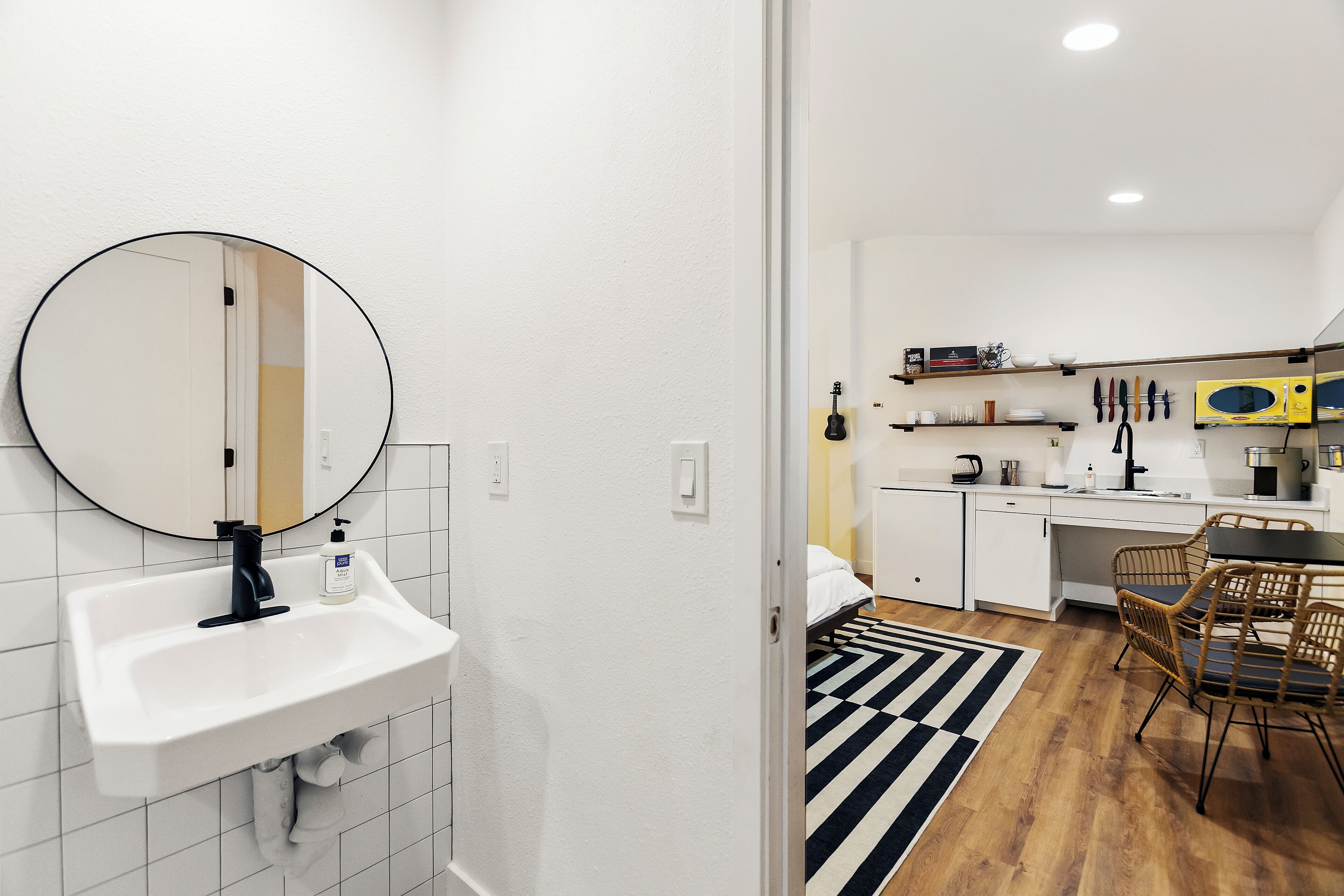A modern kitchen with white cabinets, a black countertop, and a yellow microwave.