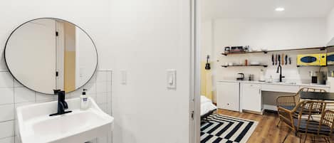A modern kitchen with white cabinets, a black countertop, and a yellow microwave.