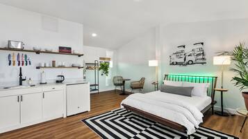 A modern bedroom with a bed, bedside tables, a desk, and a chair.