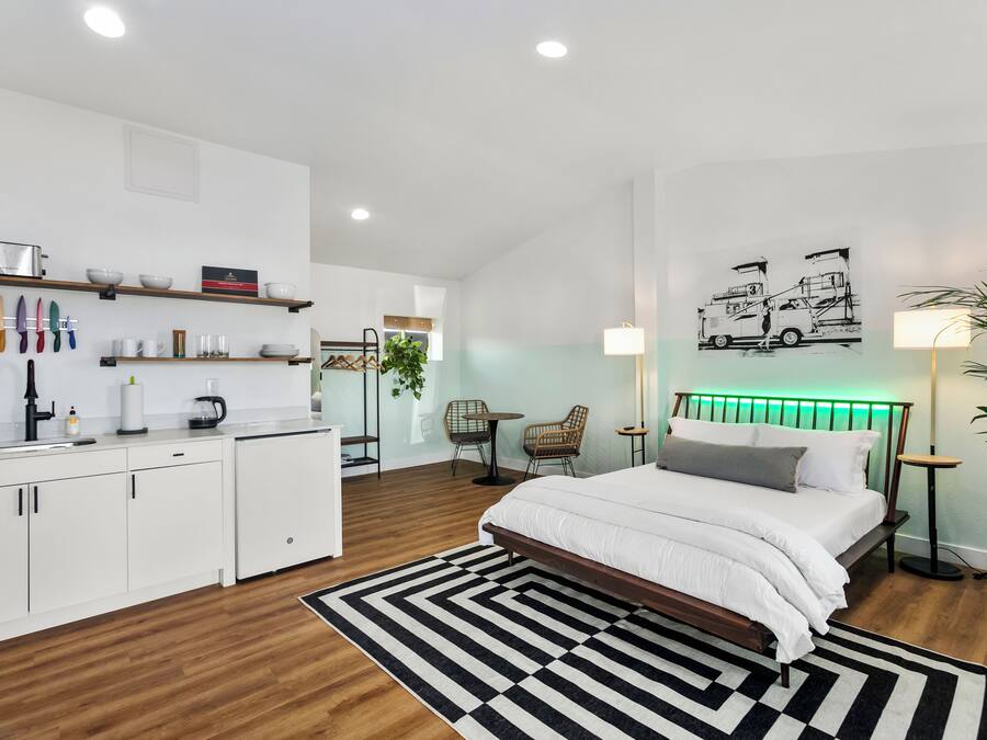 A modern bedroom with a bed, bedside tables, a desk, and a chair.