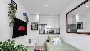 A modern, compact bedroom with a bed, bedside table, and a TV mounted on the wall.