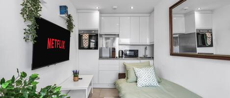 A modern, compact bedroom with a bed, bedside table, and a TV mounted on the wall.