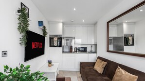 A modern living room with a brown sofa, a white coffee table, and a TV mounted on the wall displaying "NETFLIX".