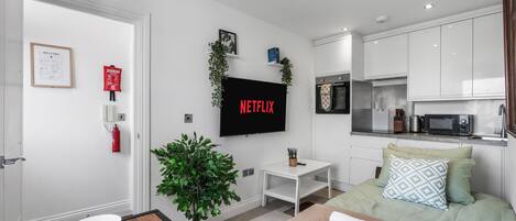 Een moderne woonkamer met een flatscreen televisie, een salontafel, een bank en een eethoek met borden en een croissant.