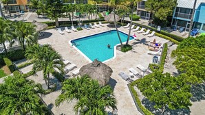 Ein Resort mit Swimmingpool, Liegestühlen und Palmen.