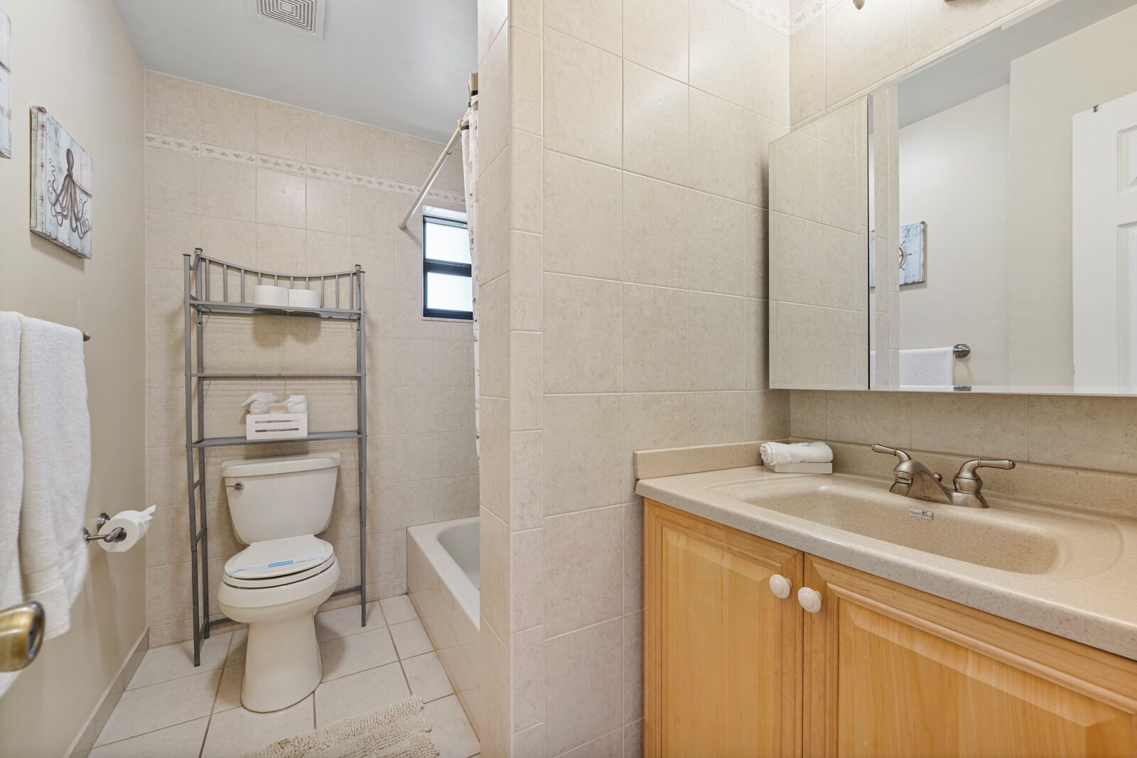 Ein Badezimmer mit Toilette, Dusche, Waschbecken mit Spiegel und Handtuchhalter.
