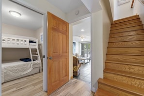 Une pièce avec des lits superposés, une porte en bois et un escalier.