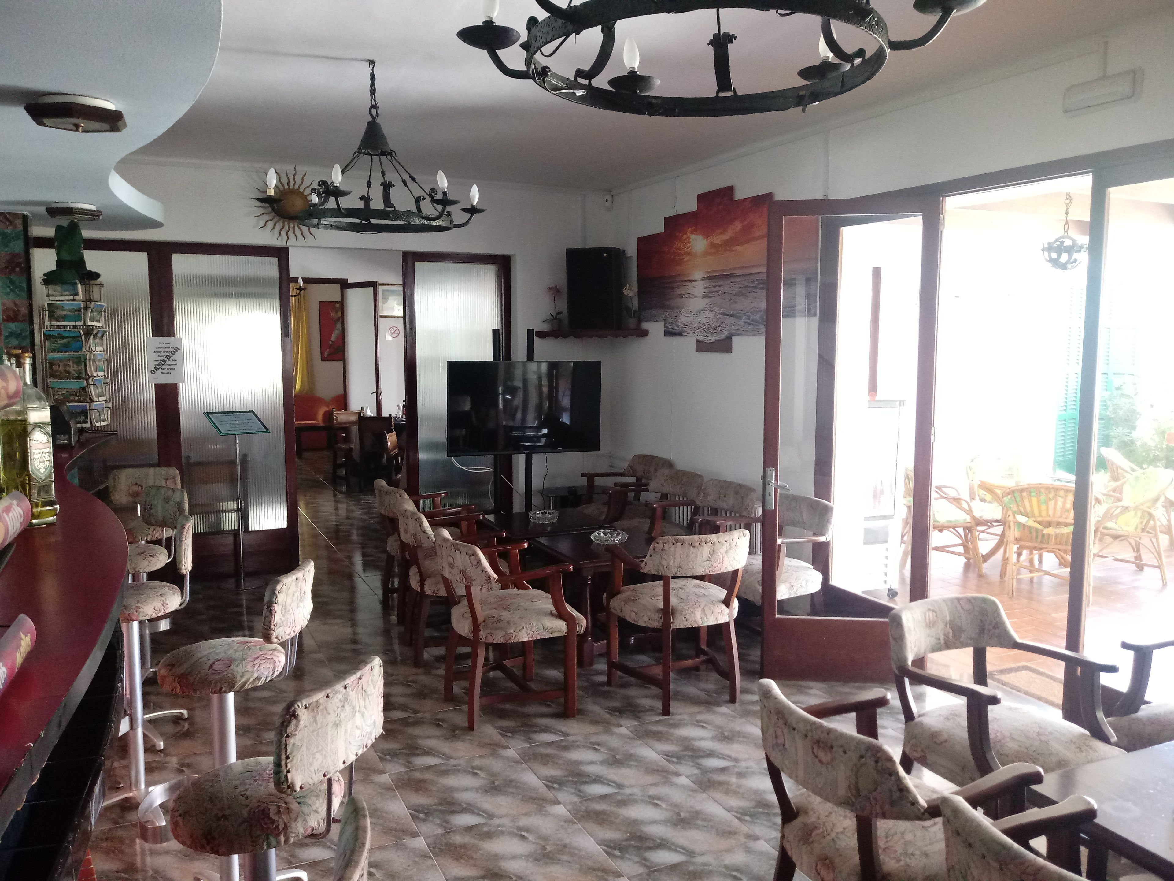 A dining area with a long table and chairs, a television, and a chandelier.