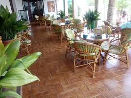 Un amplio espacio interior con mobiliario de mimbre y plantas en macetas.