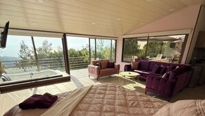 A modern bedroom with a large bed, two sofas, and a balcony with a view. - Amaruna Lb - Aroma (Ghadras)