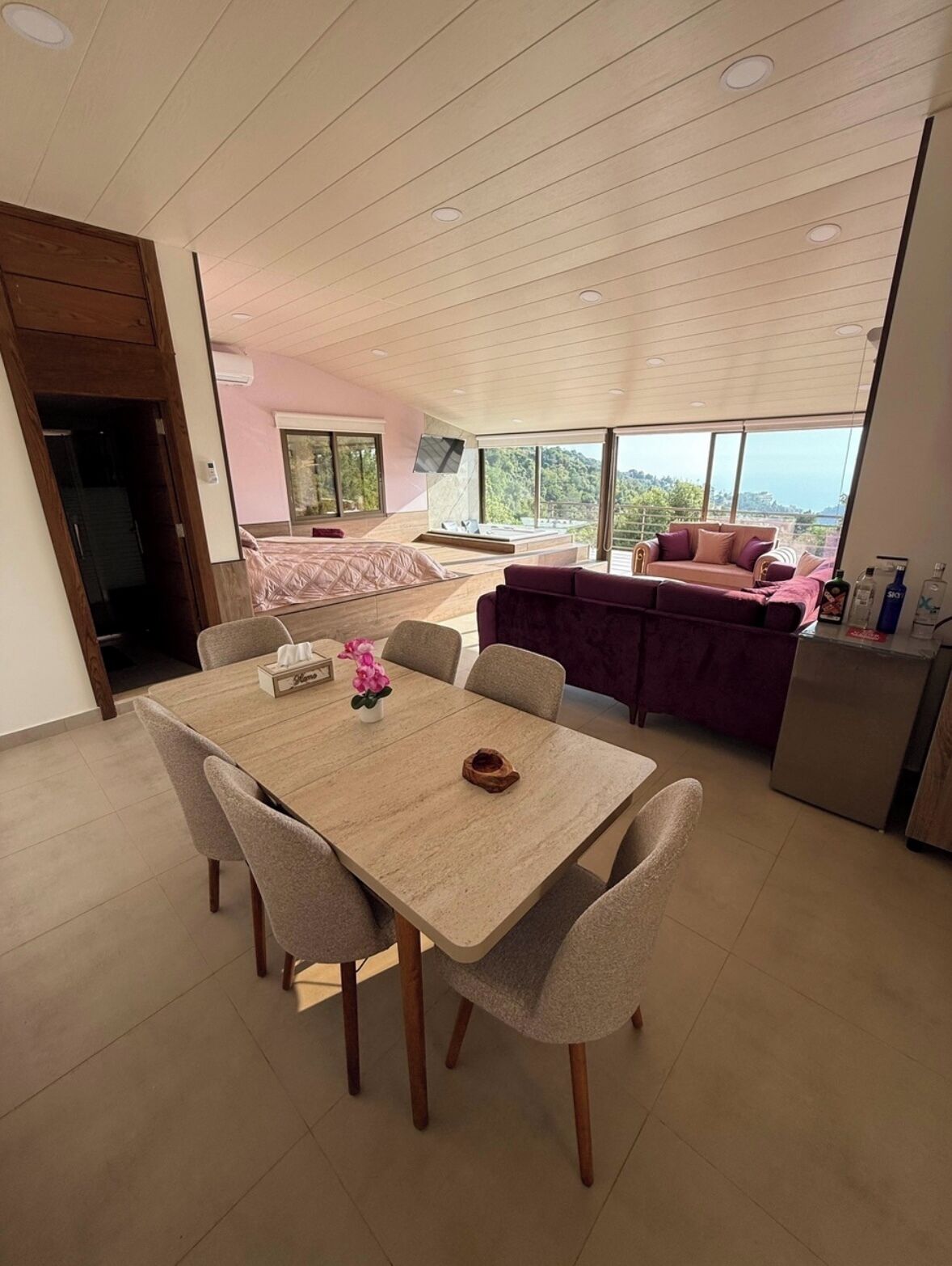 Una habitación amplia con una gran mesa de comedor, un sofá y un televisor instalado en la pared.