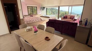 Una habitación amplia con una gran mesa de comedor, un sofá y un televisor instalado en la pared.