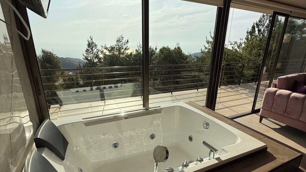 A modern bathroom with a large bathtub, a glass-enclosed shower area, and a view of the outdoors. - Amaruna Lb - Aroma (Ghadras)