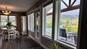 A spacious dining area with a large window overlooking a scenic landscape, a chandelier, and a potted plant. - Stillwater River Front Montana Home (Nye)